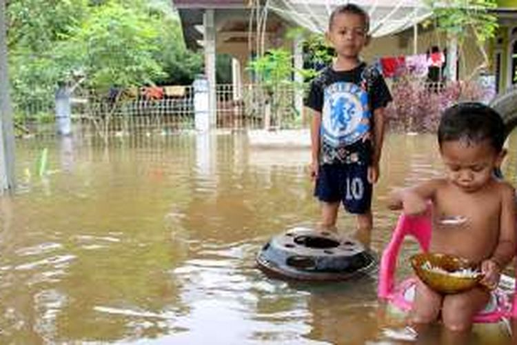 Anak-anak dari korban banjir di Desa Masjid Baro, Kecamatan Samatiga, Aceh Barat, makan di tengah genangan banjir, Jumat (26/8/16).  