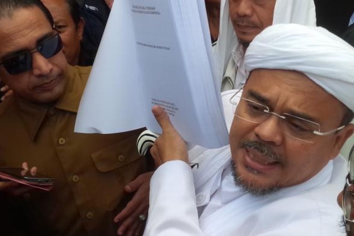 Pemimpin Front Pembela Islam Rizieq Shihab menunjukkan tesisnya sebelum diperiksa oleh penyidik Polda Jawa Barat, Senin (13//2/2017). 