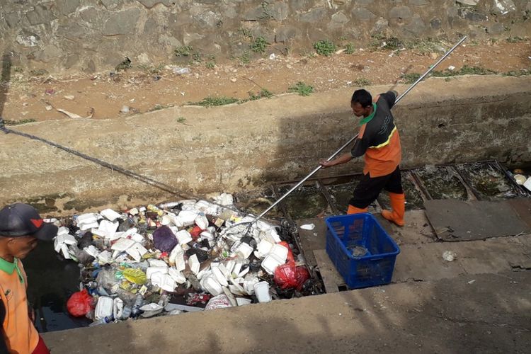 Petugas UPK Badan Air tengah mengangkut sampah yang memenuhi saluran air di kawasan Pal Meriem, Jakarta Timur, yang mengarah ke Kali Sentiong atau Kali Item, Jumat (3/8/2018).