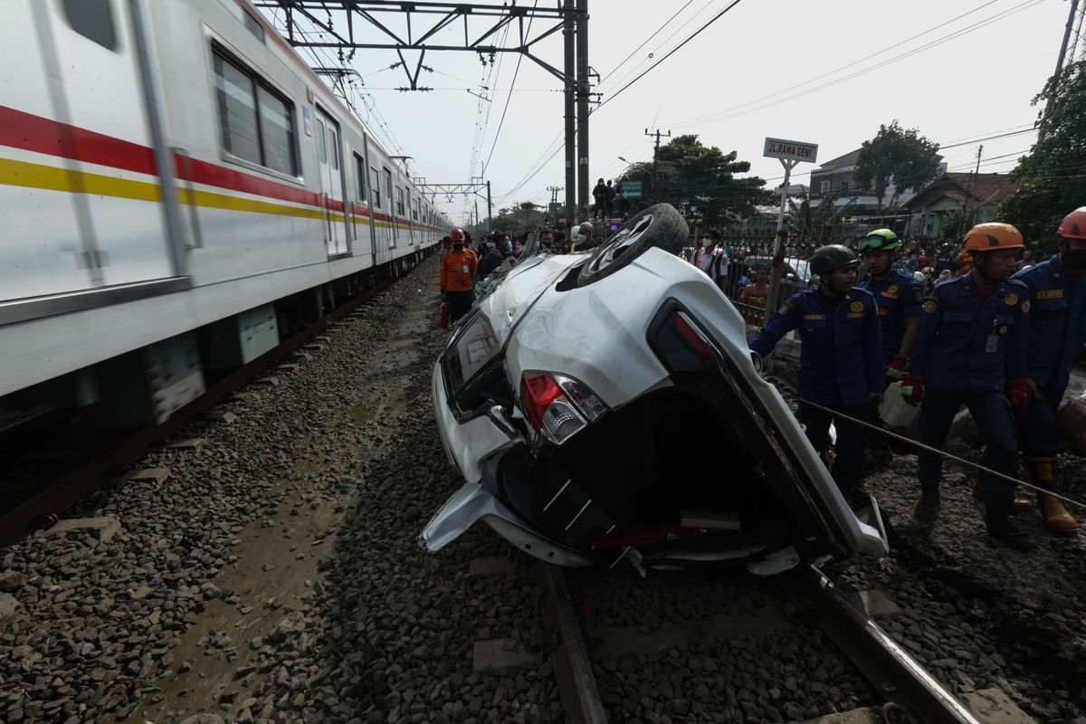 Petugas melakukan evakuasi mobil Mobilio dengan nomor polisi B 1563 NYZ yang tertabrak KRL Commuter Line di Depok, Jawa Barat, Rabu (20/4/2022). Akibat kejadian ini jadwal KRL dari Depok menuju Jakarta terganggu.