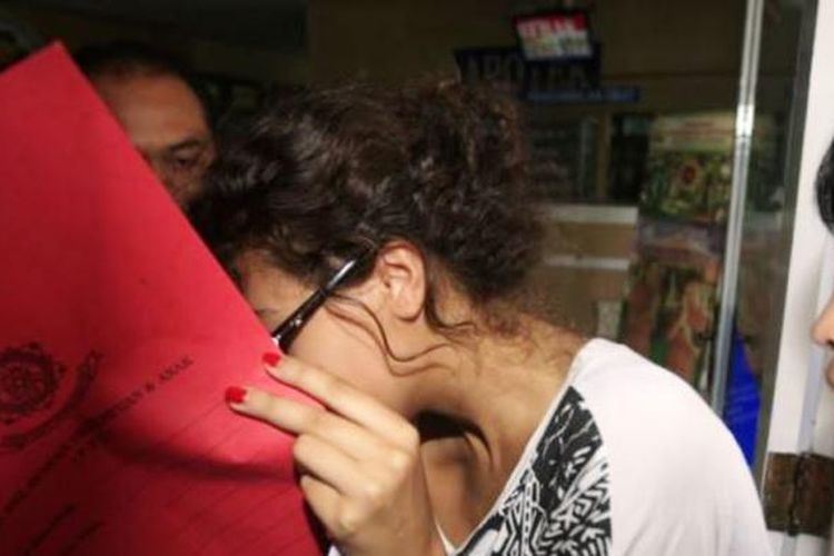 Heather Mack, menutupi wajahnya, saat dibawa polisi terkait pembunuhan ibunya Sheila von Wiese-Mack di Bali (15/8/2014).