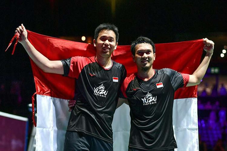 Ganda putra Indonesia Hendra Setiawan (kiri) dan Mohammad Ahsan berpose dengan bendera merah putih usai mengalahkan ganda putra Jepang Takuro Hoki dan Yugo Kobayashi pada babak final Kejuaraan Dunia Bulu Tangkis 2019 di St Jakobshalle, Basel, Swiss, Minggu (25/8/2019). Ahsan/Hendra menjadi juara dunia ganda putra usai menang dengan skor 25-23, 9-21, 21-15.