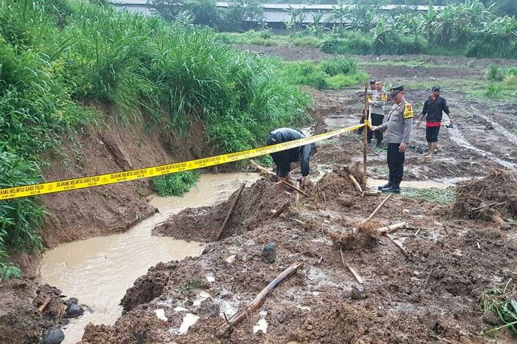 Sejumlah petugas Polsek Nyalindung sedang memasang garis polisi di tempat kejadian perkara tiga anak meninggal tenggelam di selokan milik perusahaan peternakan ayam di Kampung Warungwaru, Desa Neglasari, Kecamatan Nyalindung, Sukabumi, Jawa Barat, Kamis (11/1/2024).