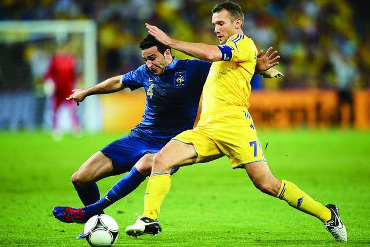 Bek Perancis, Adil Rami (kiri), berebut bola dengan penyerang Ukraina, Andriy Shevchenko, pada laga Piala Eropa 2012 di Donetsk, Jumat (15/6). Perancis menang 2-0. 
