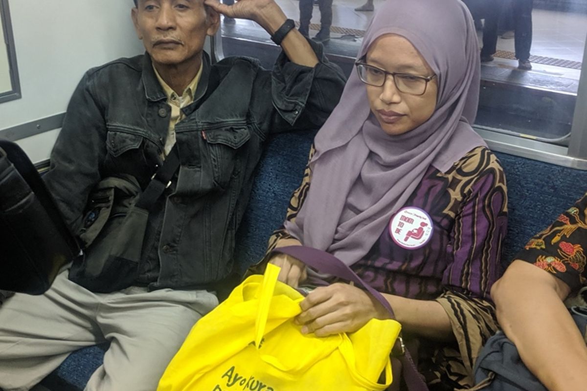 Seorang wanita yang mengenakan pin khusus ibu hamil di KRL diberi tempat duduk oleh penumpang lain.