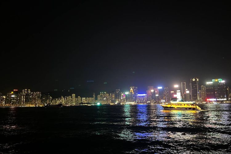 Kapal Melintas di Kawasan Pelabuhan Victoria Hong Kong dengan latar belakang gemerlap lampu gedung-gedung di Pulau Hong Kong, dilihat dari Kowloon Public Pier, Senin (12/1/2025).