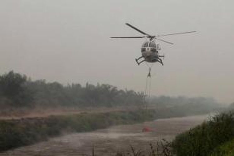 Badan Nasional Penanggulangan Bencana (BNPB) mengambil air menggunakan helikopter Bolkow BO-105 saat melakukan pemadaman dengan teknik bom air (water bombing) di Desa Pelita Jaya, Kecamatan Kubu, Kabupaten Kubu Raya, Kalimantan Barat, Rabu (21/10/2015).