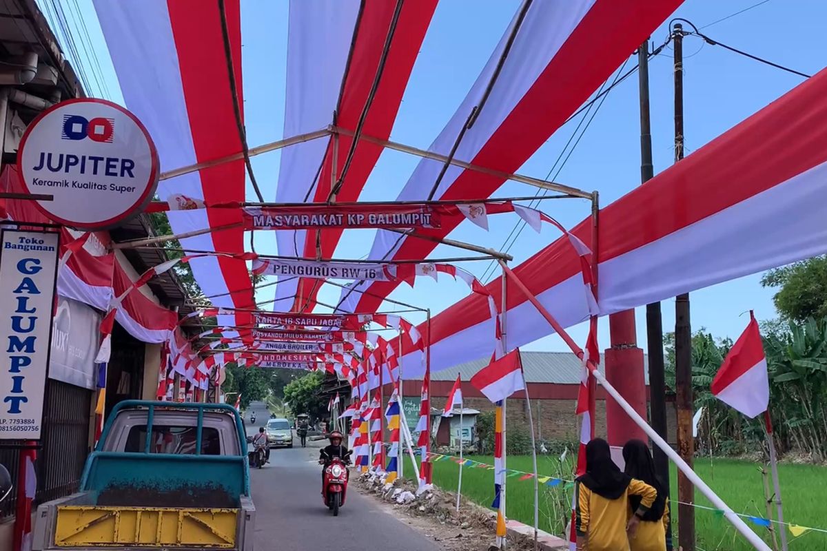 Bendera merah putih dengan lebar 4 meter dan panjang 70 meter terpasang di sepanjang Jalan Raya Galumpit, Desa Cileunyi Kulon, Kecamatan Cileunyi, Kabupaten Bandung, Jawa Barat. Bendera berukuran besar itu dipasang di atas 18 gapura kayu yang berjejer di Jalan Raya Galumpit, Jumat (9/8/2024)