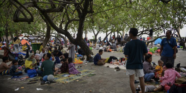 Warga beristirahat di bawah pohon di kawasan Pantai Ancol, Jakarta, Minggu (23/4/2023).