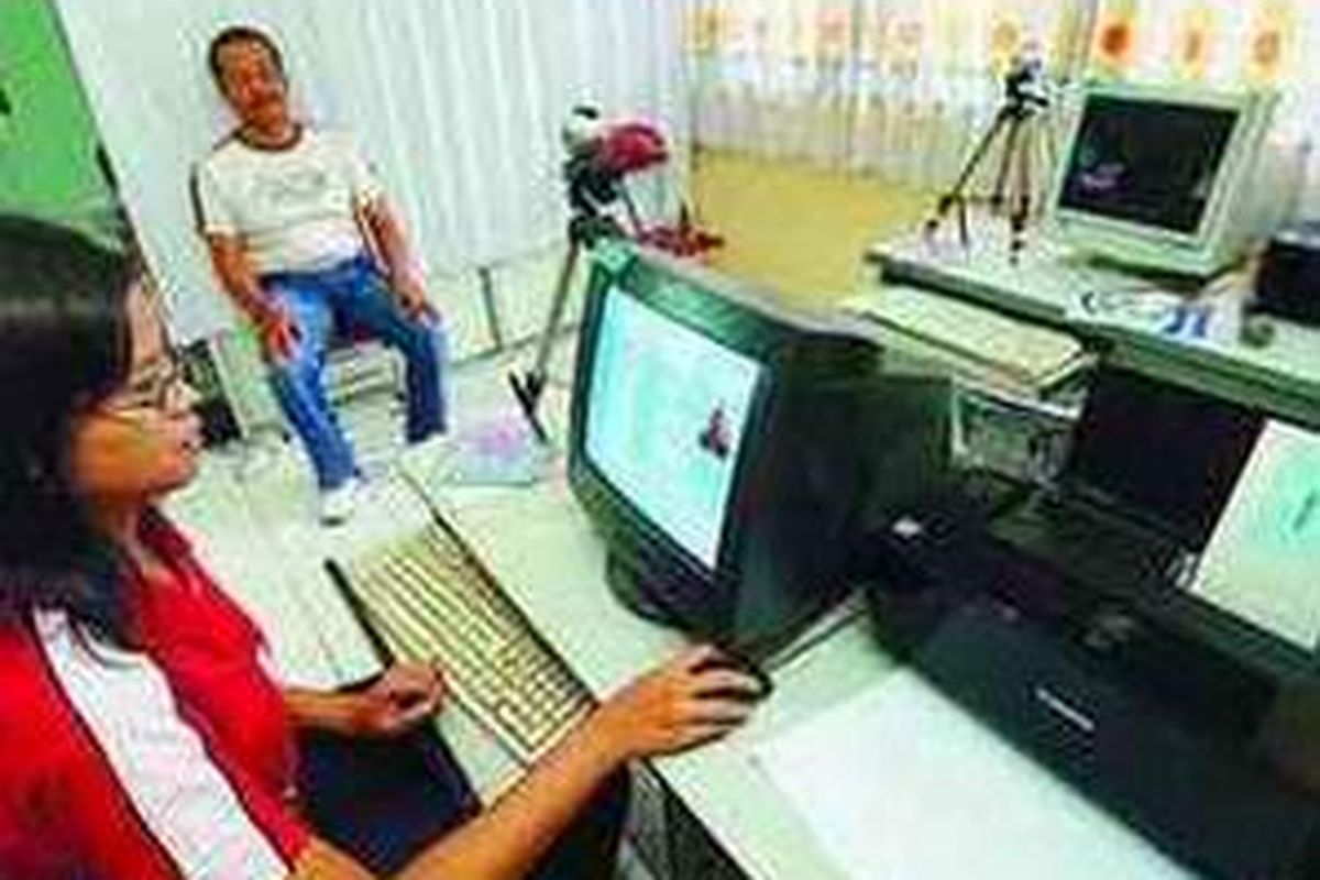 Warga yang akan mengurus KTP di Badan Pelayanan Terpadu Kabupaten Sragen, Jawa Tengah, hanya membutuhkan waktu 3-5 menit. Petugas sedang membuat foto dan memasukkan data pemohon, Jumat (15/2).