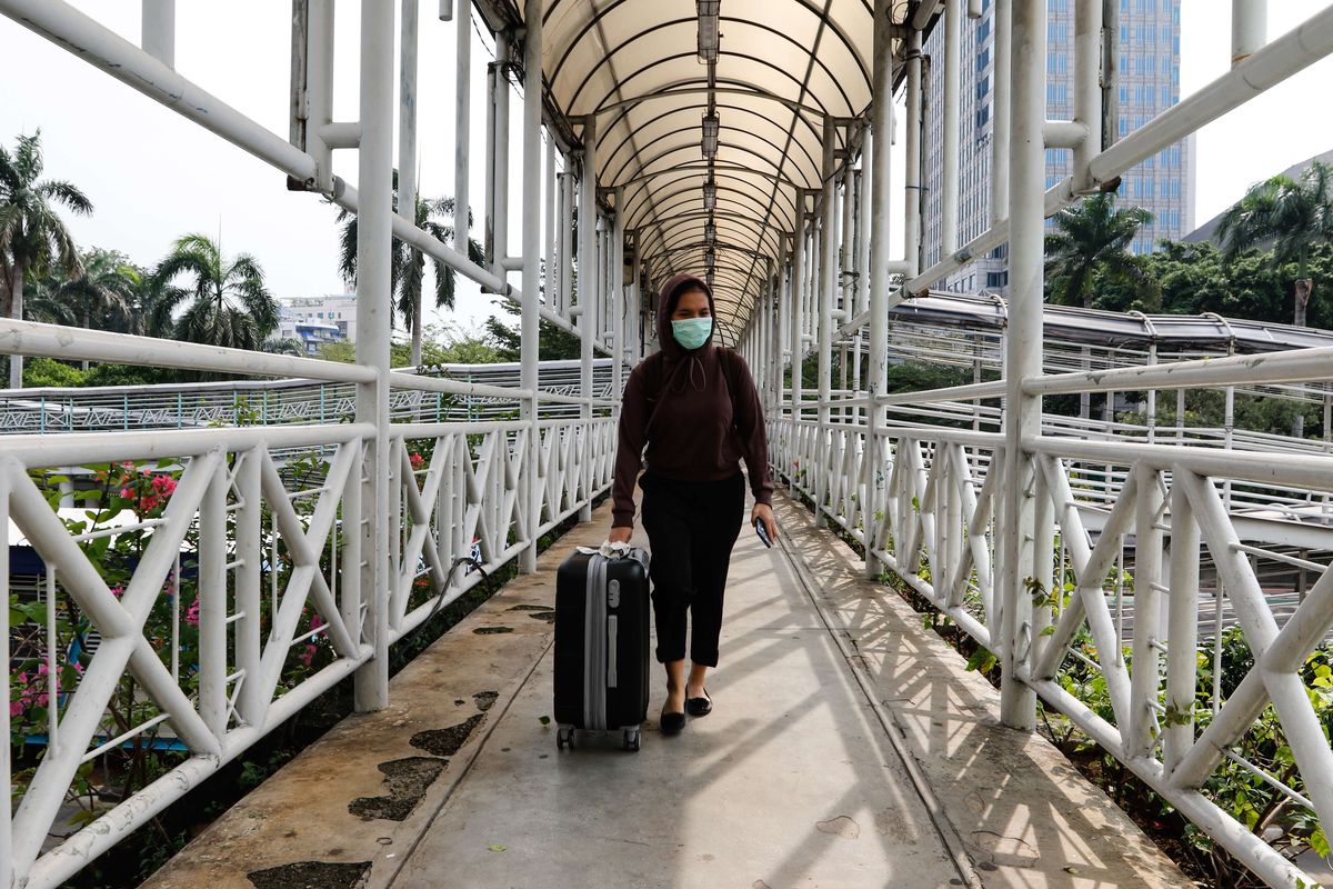 Warga melintas di jembatan penyeberangan orang (JPO) di Jalan MH Thamrin, Jakarta Pusat pada akhir pekan, Sabtu (18/4/2020). Pemerintah Provinsi (Pemprov) DKI Jakarta resmi menerapkan pembatasan sosial berskala besar ( PSBB) mulai 10 hingga 23 April 2020. Dampak dari adanya aturan ini, membuat kondisi dan situasi lalu lintas pada akhir pekan menjadi lengang dan sepi.