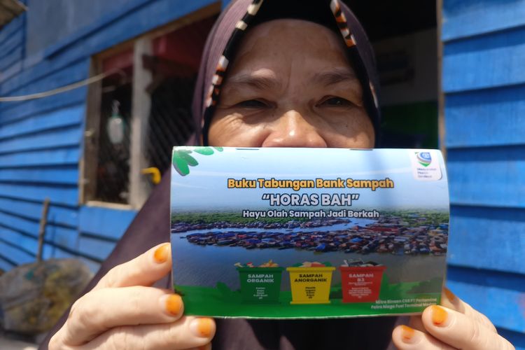Hamidah (53), menujukkan buku tabungan Bank Sampah Horas Bah di Lingkungan 12, Kampung Nelayan, Kecamatan Medan Belawan, Kota Medan, Sumatera Utara, Minggu (26/10/2025). Bank Sampah Hora Bah tidak hanya meningatkan penghasilan ekonomi Hamidah, tapi juga menambah keahliannya dalam mengelola sampah hingga menjadi kerajinan tangan.