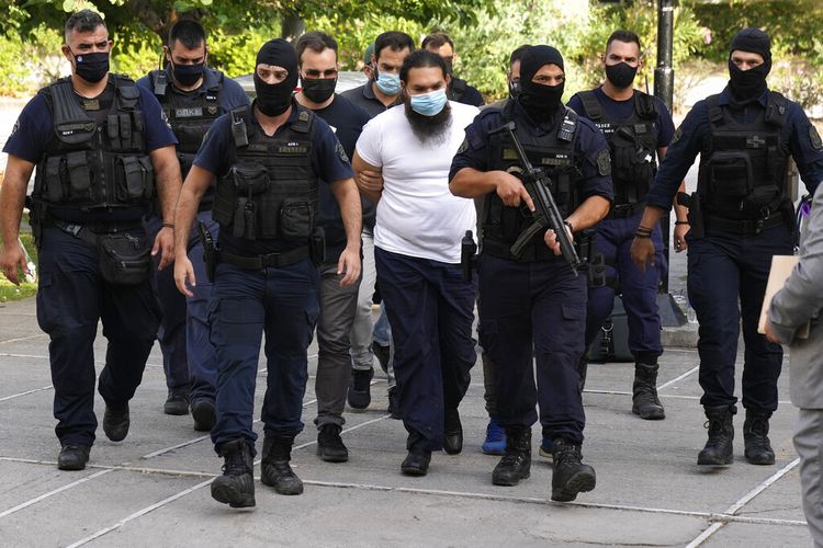 Petugas polisi mengawal seorang tersangka ke kantor kejaksaan di sebuah pengadilan di Athena, Kamis, 24 Juni 2021. 
