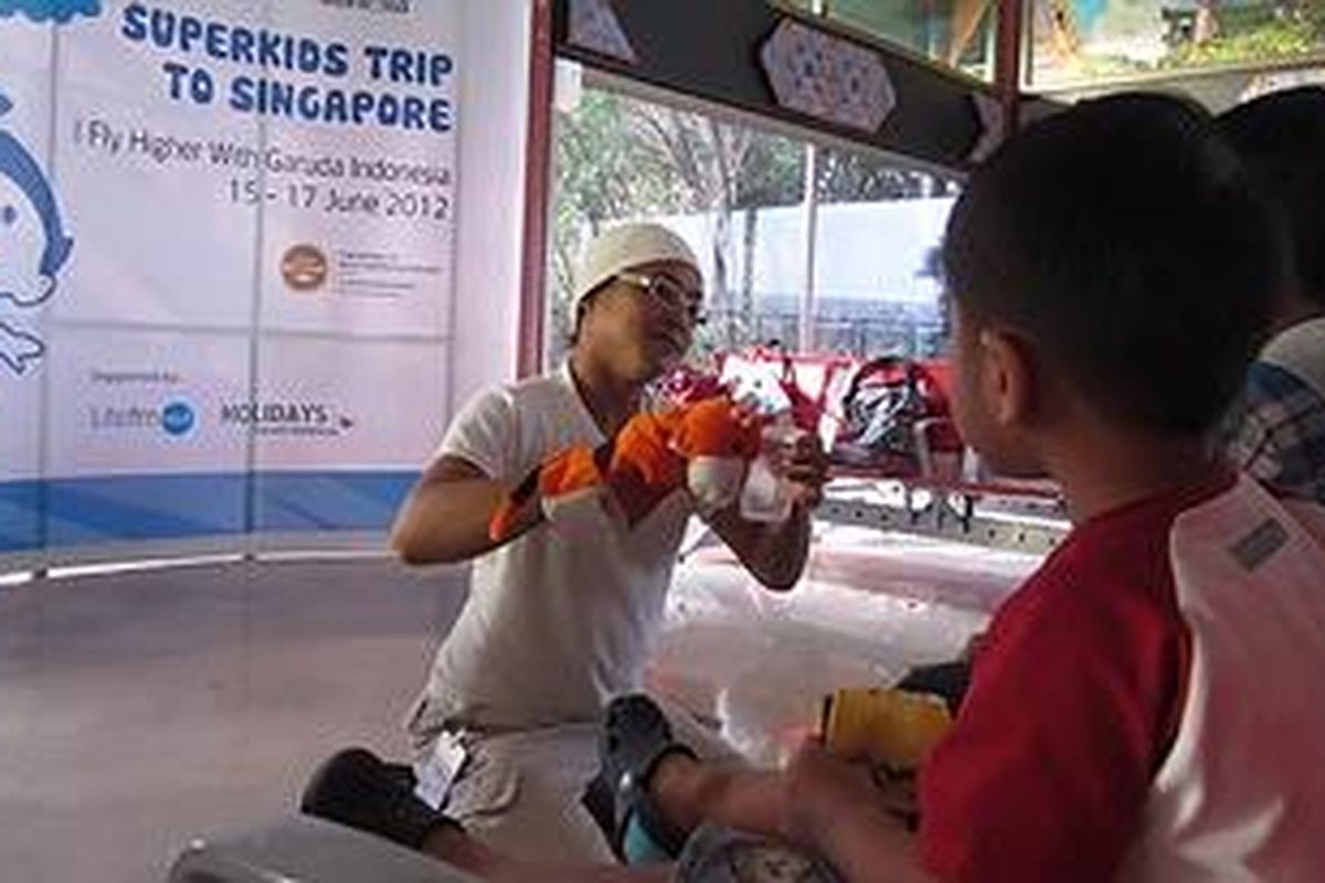 Peserta tur Superkids mendapatkan kesempatan mendengar cerita juga sulap di ruang tunggu sebelum boarding, dalam keberangkatan menuju Singapura, Jumat, 15/6/2012.