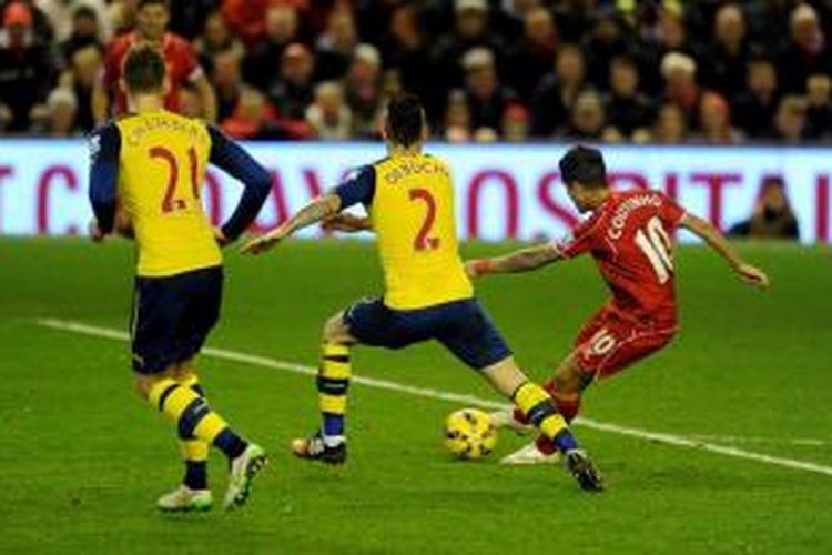 Gelandang Liverpool, Philippe Coutinho (kanan) coba melepaskan tembakan meski diadang oleh barisan pertahanan Arsenal saat kedua tim bertemu, Desember 2014.