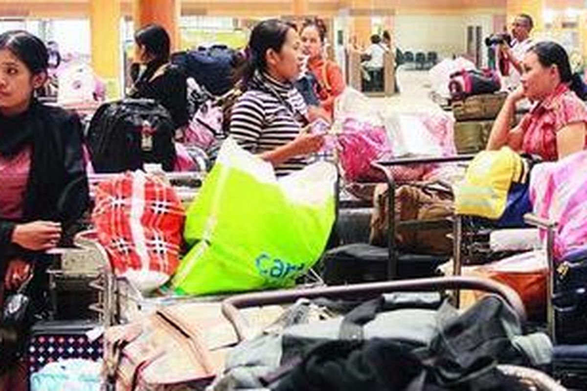 Tenaga kerja Indonesia berdiri menjaga barang bawaan mereka sambil menunggu giliran pulang ke daerah asal menggunakan mikrobus angkutan khusus TKI di Gedung Pendataan Kepulangan TKI di Selapajang, Kota Tangerang, Banten, Rabu (28/10).