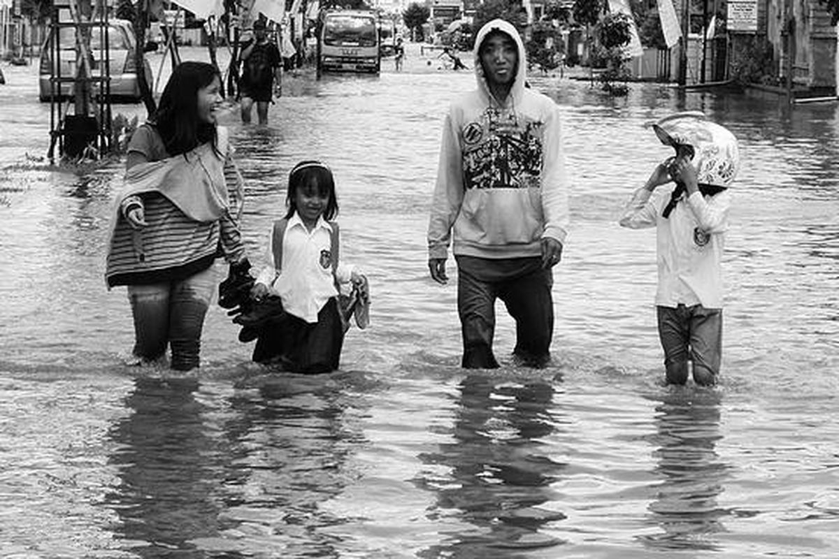 Dillah (kedua dari kiri) basah kuyup akibat menerobos banjir di Jalan Jenderal Ahmad Yani, Samarinda, Kalimantan Timur, Senin (10/11). Sekolah-sekolah di sepanjang jalan tersebut tidak libur meski banjir.  