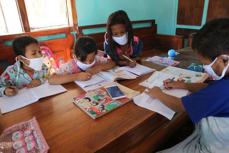 Sejumlah siswa Sekolah Dasar Negeri (SDN) di Desa Marmoyo, Kecamatan Kabuh, Kabupaten Jombang, Jawa Timur, mengerjakan tugas dengan berkelompok menggunakan handphone secara bergantian di rumah warga, Rabu (22/7/2020).