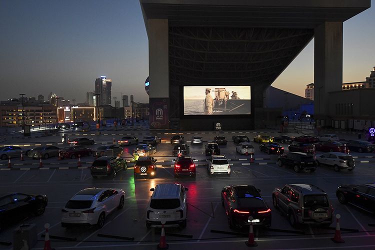 Sejumlah orang menonton film dari dalam mobil mereka di bioskop drive-in di luar Mall of Emirates di Dubai, Minggu (17/5/2020). Bioskop drive-in dengan konsep menonton film dari dalam mobil yang sempat jaya dahulu kala, kini kembali menjadi tren di berbagai negara karena pandemi virus corona.