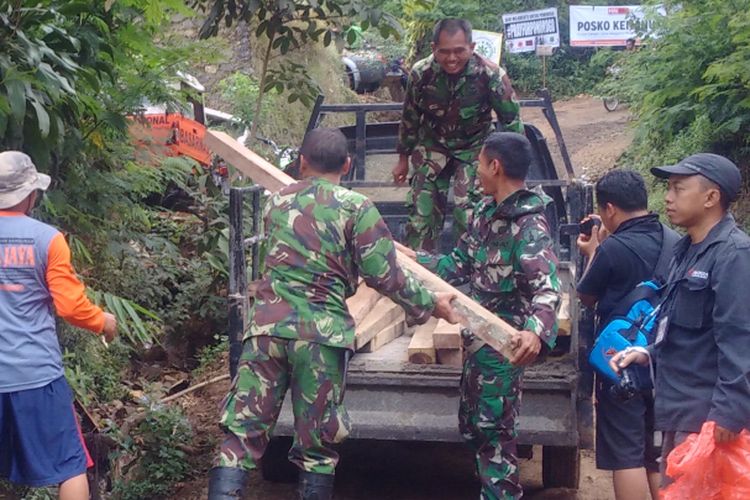 Anggota TNI AD menurunkan kayu untuk bahan pembangunan barak pengungsi korban tanah longsor di Sektor A, Desa Banaran, Kecamatan Pulung, Kabupaten Ponorogo, Jumat ( 7/4/2017) siang.