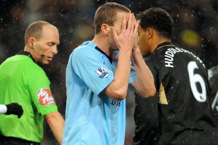 Mantan bek Manchester City Richard Dunne menutupi wajahnya.