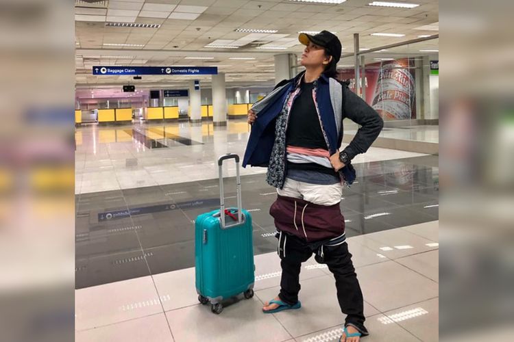 Wanita asal FIlipina ini mengenakan pakaian ekstranya karena membawa koper yang terlalu berat.