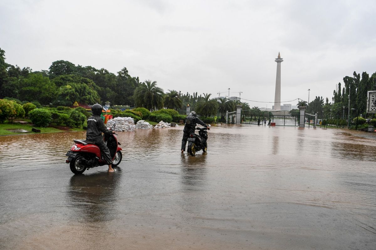 Warga mendorong motor melintasi banjir di kawasan Monas, Jalan Medan Merdeka Barat, Jakarta, Minggu (2/2/2020). Hujan deras yang mengguyur Jakarta pada Minggu (2/2/2020) pagi menyebabkan beberapa ruas jalan di ibu kota tergenang banjir dengan ketinggian 10-50 sentimeter.