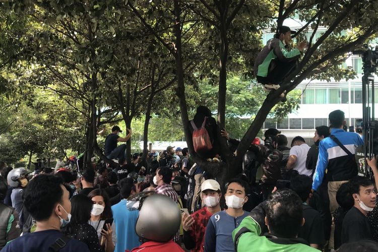 Sejumlah orang nekat memanjat pohon demi melihat rombongan pembalap MotoGP dari luar area Hotel Indonesia Kempinski, Jakarta Pusat pada Rabu (16/3/2022) pagi.