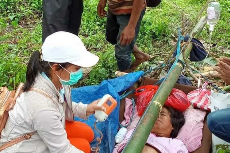 Tim medis dari Puskesmas Elpaputih memberikan pertolongan pertama bagi Yuliana Lasattira (40) di tengah hutan. Yuiliana ditandu keluarganya dari Desa Huku Kecil menuju Puskesmas Elpaputih yang jaraknya 37 kilometer pada Jumat (20/8/2021).