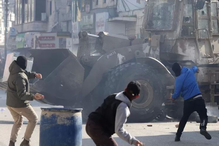 Pria-pria Palestina melempar batu di tengah bentrokan dengan tentara Israel dalam serangan Jenin awal tahun ini