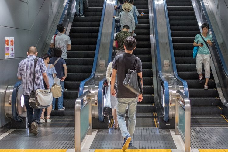 Ilustrasi orang-orang naik eskalator di salah satu stasiun kereta di Tokyo, Jepang.