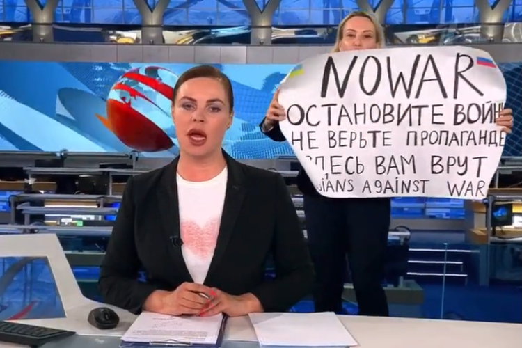 Tangkap layar Maria Ovsyannikova, seorang editor di media utama milik negara Rusia, berlari ke depan kamera dan menyela siaran langsung medianya sendiri pada Senin (14/3/2022). 
