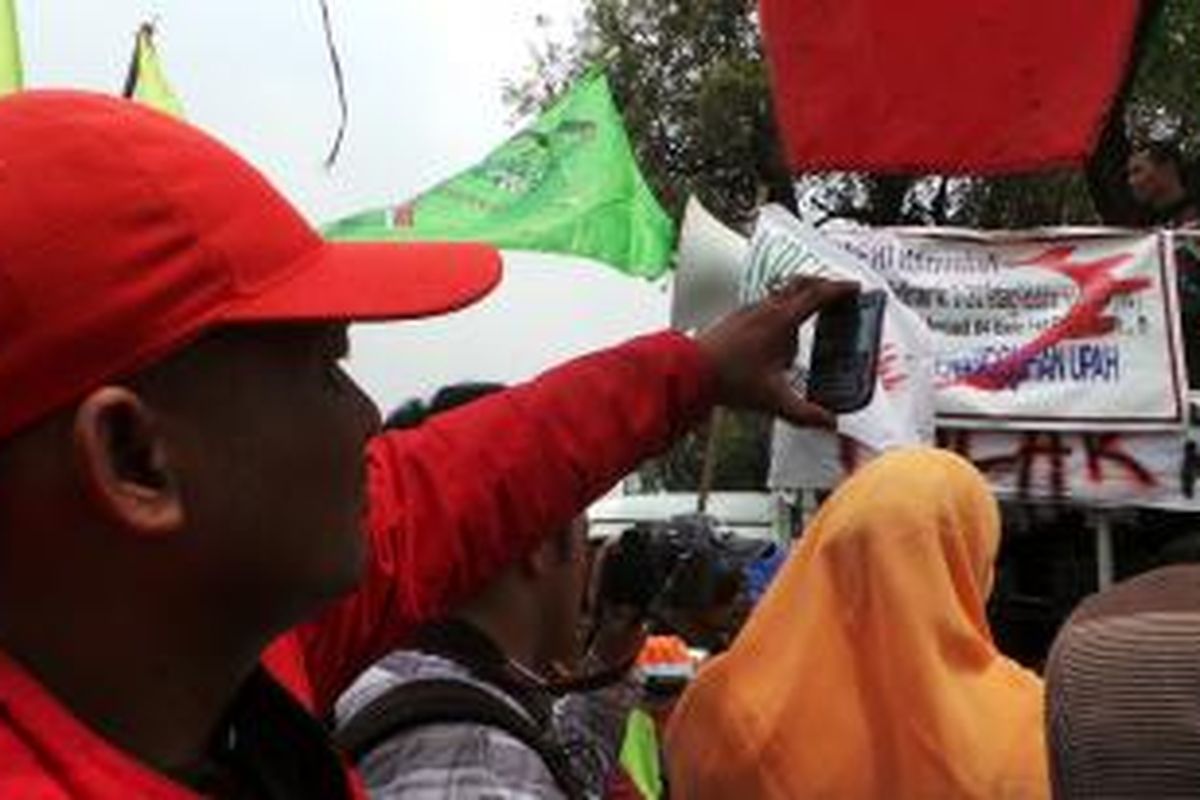 Seorang buruh tampak mengarahkan ponselnya ke arah orator dalam aksi unjuk rasa di sekitar Balaikota Jakarta, Rabu (6/11/2013).