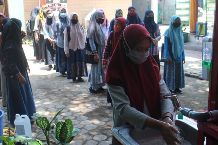 Para santriwati Ponpes Annuriyah Jember wajib cuci tangan dan menggunakan masker sebelum masuk ke ruang kelas 