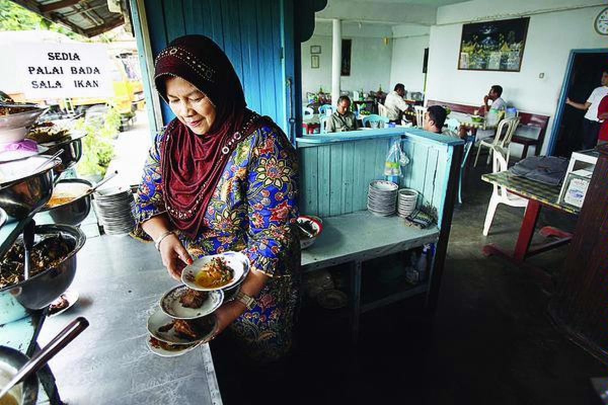 Rosna, pemilik Warung Onang, sedang menyiapkan hidangan.