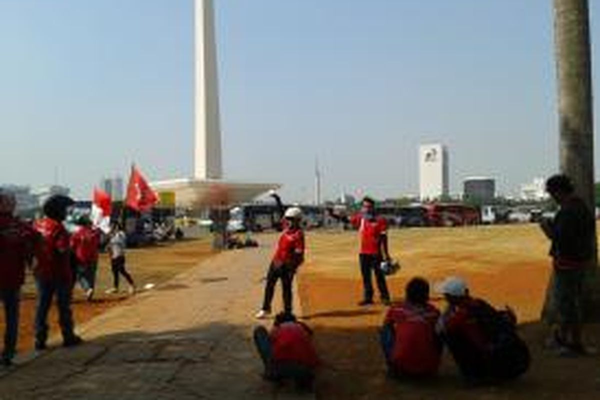 Beberapa buruh tampak berfoto dengan latar belakang Tugu Monas dan beberapa lainnya memotret rekan mereka, Selasa (1/9/2015).