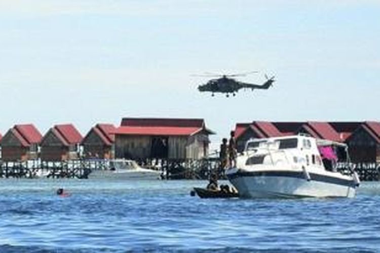 Helikopter polisi Malaysia terbang di atas deretan penginapan di pulau wisata Mabul di negara bagian Sabah lokasi penembakan yang menewaskan seorang polisi.