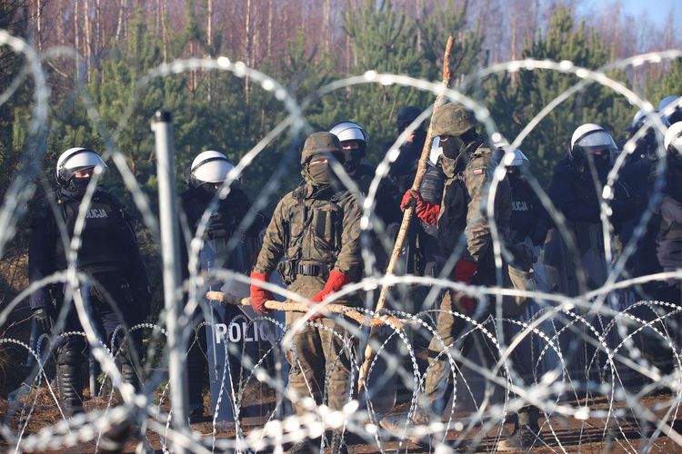 Personel keamanan berjaga di balik pagar kawat berduri di perbatasan Belarus-Polandia, tempat ratusan migran berkumpul untuk memasuki Polandia, Selasa (9/11/2021). Polandia dan negara-negara Uni Eropa (UE) menuduh Belarus mendorong para migran untuk secara ilegal melintasi perbatasan sebagai pembalasan atas sanksi yang dijatuhkan UE kepada Minsk atas pelanggaran HAM.