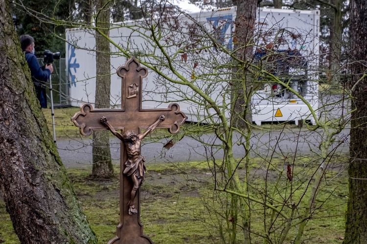 Sebuah salib berada di depan kontainer pendingin berisi jenazah korban Covid-19 di pemakaman Hanau, dekat Frankfurt, Jerman pada 17 Desember 2020. Jenazah korban virus corona terpaksa ditempatkan di sana setelah kamar mayat rumah sakit mulai penuh.