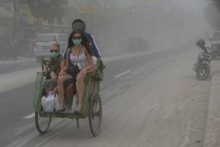 Wisatawan asing menaiki becak melintas di Jalan Jenderal Sudirman Yogyakarta yang diselimuti abu vulkanik dari letusan Gunung Kelud Jumat (14/2/2014).