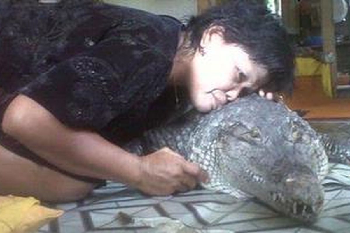 Aminah tengah memeluk Becce, seekor buaya yang sudah 4 tahun hidup bersamanya di dalam rumah, di Parepare.