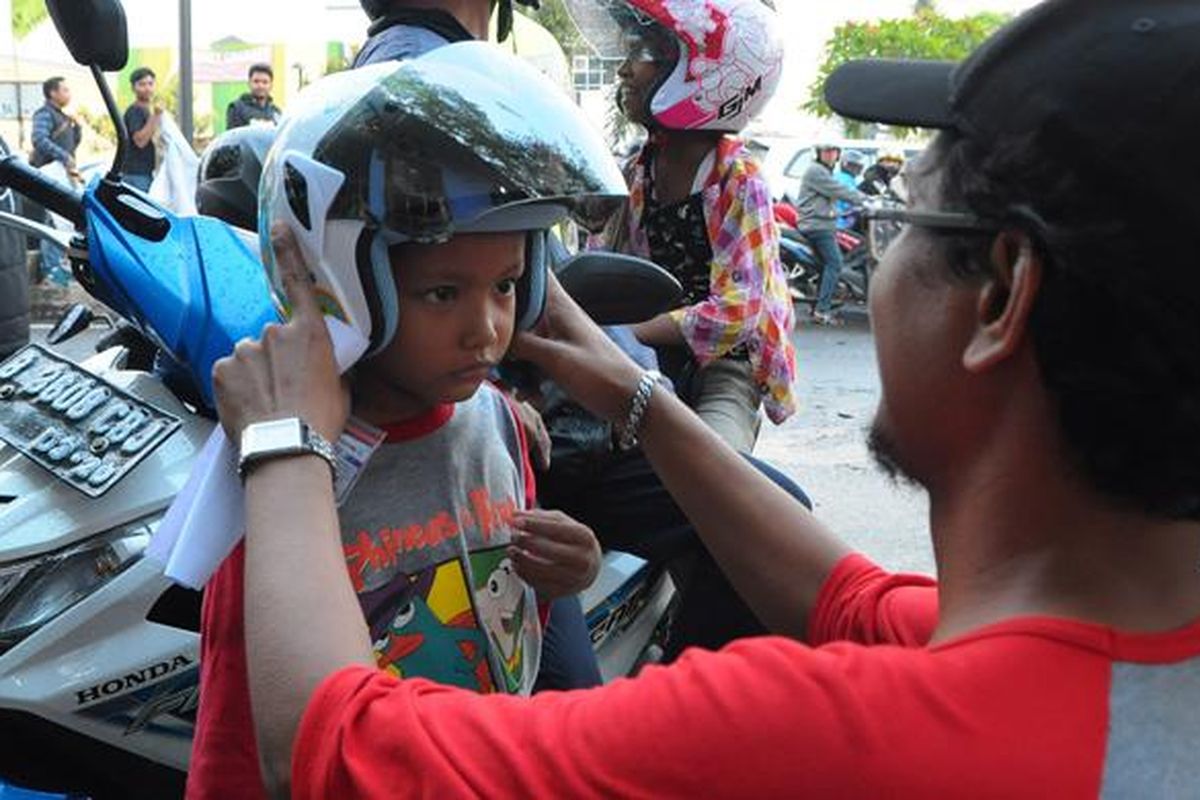 Kutu Community membagikan helm gratis untuk anak-anak di jalan raya.