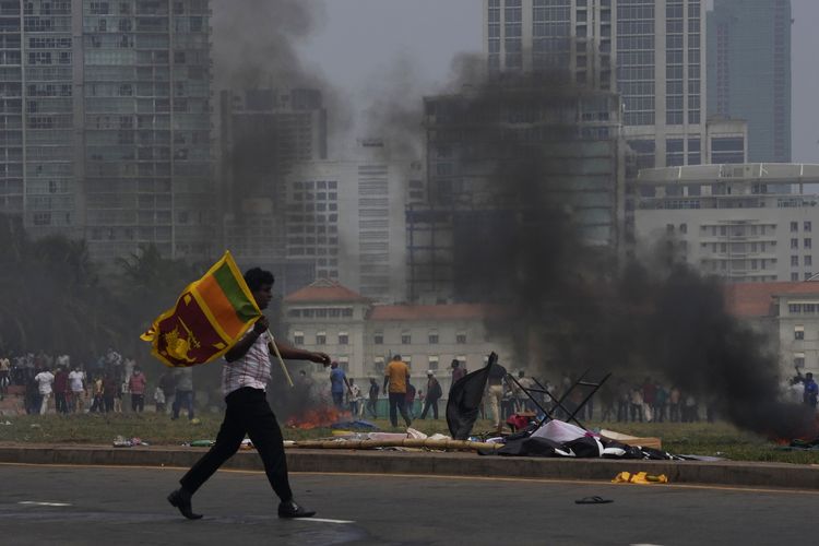 Seorang pendukung Pemerintah Sri Lanka membawa bendera negara setelah bentrok dengan massa anti-pemerintah di luar kantor presiden di Colombo, Sri Lanka, Senin (9/5/2022).