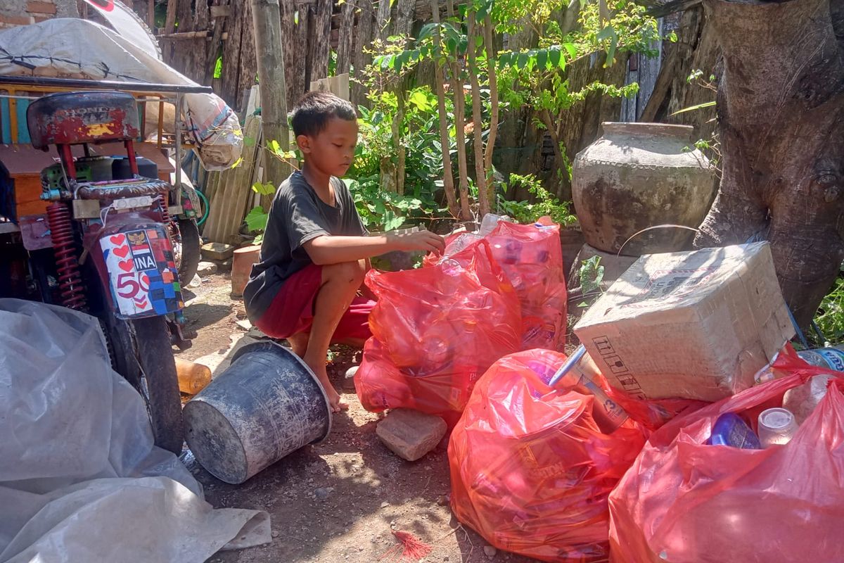 Muhammad Ilun Zainul Huda (11), bocah asal Desa Gejagan, Kecamatan Loceret, Kabupaten Nganjuk, Jawa Timur, saat menata rongsokan di kediamannya, Kamis (2/5/2024)