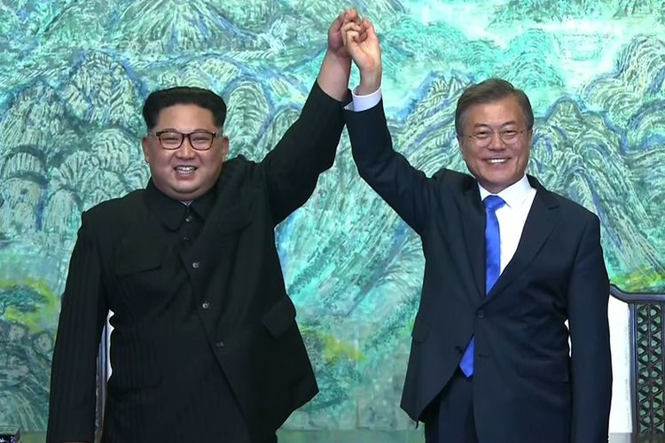 Pemimpin Korea Utara Kim Jong Un (kiri), dan Presiden Korea Selatan Moon Jae In berpegangan tangan dalam Konferensi Tingkat Tinggi (KTT) Antar-Korea di Panmunjom, Jumat (27/4/2018).