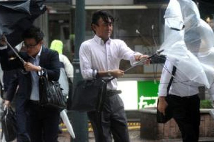 Para pengusaha Jepang berjalan melawan angin dan hujan saat Topan Wipha mendera Tokyo, Rabu.