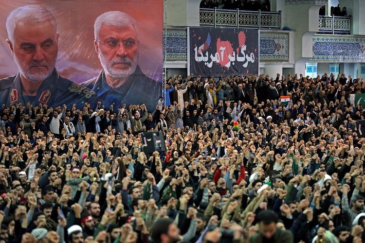 Spanduk bergambar Jenderal Qassem Soleimani, kiri, dan komandan milisi senior Syiah Irak Abu Mahdi Al Muhandis , yang tewas di Irak dalam serangan pesawat tak berawak AS pada 3 Januari 2020 serta sebuah spanduk berbahasa Persia yang artinya Matilah Amerika, di Masjid Agung Imam Khomeini di Teheran, Iran, Jumat, 17 Januari 2020.