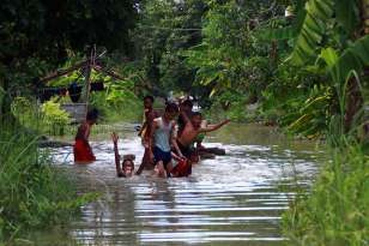 Anak-anak malah asyik bermain air banjir yang menggenangi rumahnya di Desa Bungah, Kecamatan Bungah, Gresik.