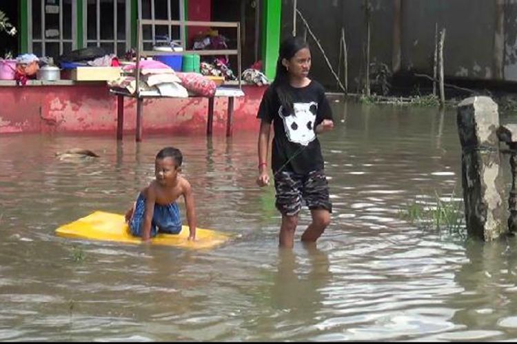 Dua bocah di Dusun Canggu Kecamatan Manggar Belitung Timur saat melintasi banjir di halaman rumah mereka.