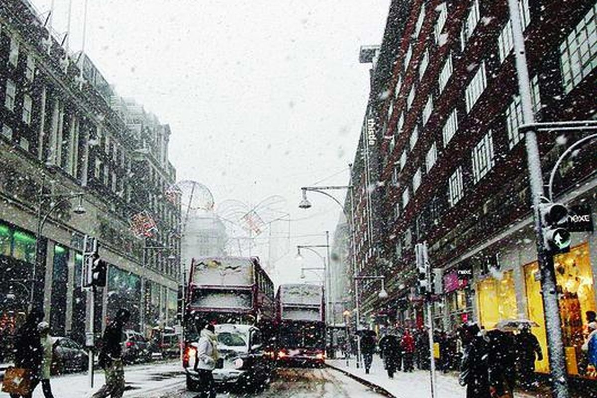 Warga menyeberang jalan di pusat perbelanjaan Oxford Street, Kota London, Inggris, saat salju turun, Sabtu (18/12). Tebalnya salju yang turun tersebut menyebabkan sejumlah penerbangan di Bandara Heathrow dan Gatwick, London, ditunda.